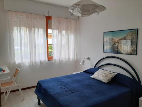 a bedroom with a blue bed and a desk and window at Villa Lilly in Grado