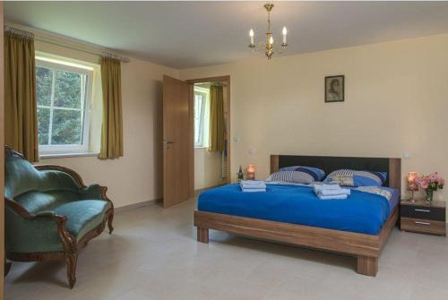 um quarto com uma cama azul e uma cadeira em Schloss Thorn em Palzem