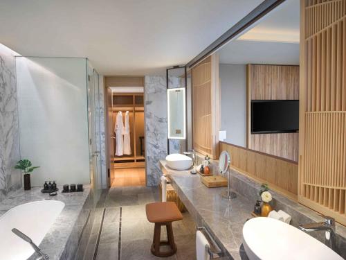 a bathroom with two sinks and a tv on the wall at ANA InterContinental Beppu Resort & Spa by IHG in Beppu