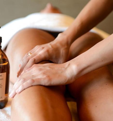 a woman sitting on a bed with her hands on her legs at Corallo Wellness Hotel in Diano Marina