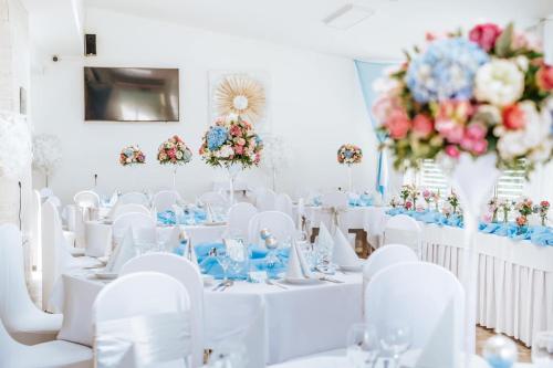 a room with white tables and white chairs and flowers at Penzion Adriana in Nové Mesto nad Váhom