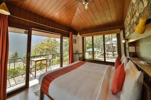 a bedroom with a bed and a balcony with windows at Atali Ganga in Rishīkesh