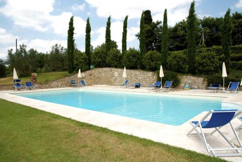a large swimming pool with chairs and umbrellas at Residenza d'Epoca Il Cassero in Lucignano