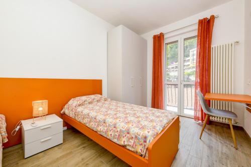 een slaapkamer met een bed, een bureau en een raam bij Tre passi dal lago 2 in Toscolano Maderno