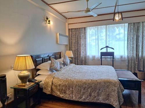 a bedroom with a bed and a large window at The Heritage Club - Tripura Castle Hotel and Spa in Shillong