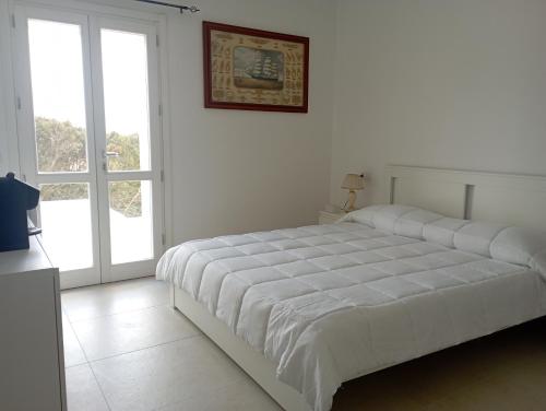 a white bedroom with a large bed and a window at Sea & Country Rooms in Golfo Aranci