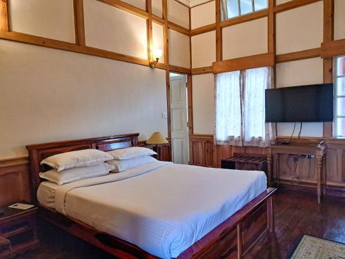 a bedroom with a large bed and a flat screen tv at The Heritage Club - Tripura Castle Hotel and Spa in Shillong