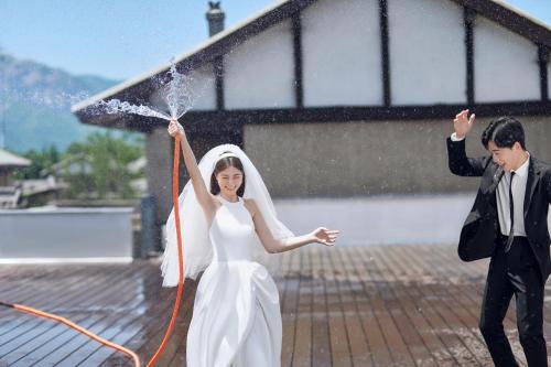 a bride and groom playing with a water hose at Yuncheng Yunxi Furusato-Banma Resort in Yuncheng