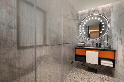a bathroom with a shower with a sink and a mirror at Hotel Indigo Guangzhou Haixinsha by IHG - Free Shuttle Bus to Canton Fair Complex during Canton Fair period in Guangzhou