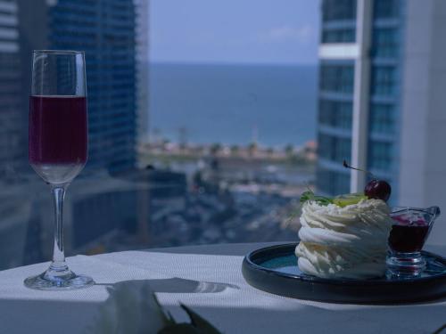 a table with a plate of food and a glass of wine at New Wave Hotel in Batumi