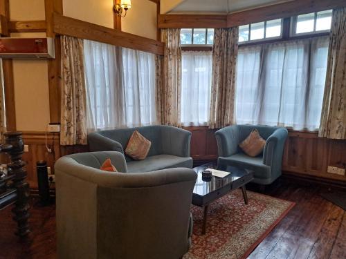 a living room with two chairs and a table at The Heritage Club - Tripura Castle Hotel and Spa in Shillong