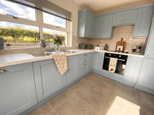 a kitchen with white cabinets and a sink and a window at NEW - The Gate Lodge at Dunnanew - 4 star- Sleeps 5 in Seaforde