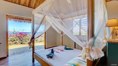 a bedroom with a canopy bed with a view of the ocean at Superbe villa avec ponton privé in Andilana