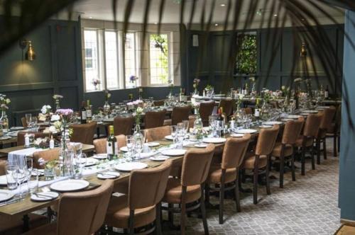 - une longue table dans une pièce avec des chaises et des tables dans l'établissement The Vines Hotel, à Alvescot