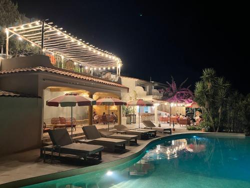 a swimming pool with chairs and umbrellas next to a house at Hotel Riva Beach in Porto-Vecchio