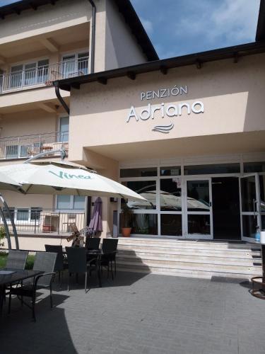 a restaurant with tables and umbrellas in front of a building at Penzion Adriana in Nové Mesto nad Váhom