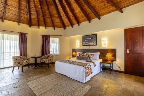a bedroom with a bed and a table and chairs at Sentrim Elementaita Lodge in Elmenteita