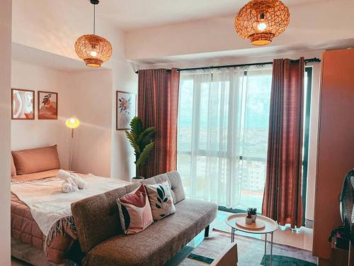 een slaapkamer met een bed, een bank en een raam bij Studio Unit Viceroy Residences McKinley Hill BGC in Manilla