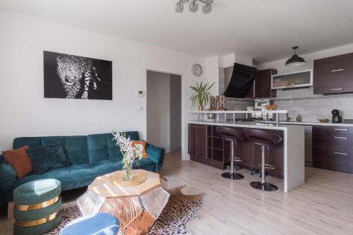 a living room with a blue couch and a kitchen at Bright Condo in Nusle by Prague Days in Prague