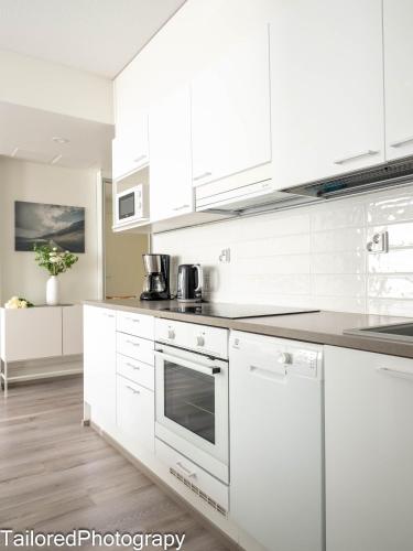 a white kitchen with white cabinets and appliances at Uusi asunto ydinkeskustassa, Wifi, ilmainen pysäköinti in Lappeenranta