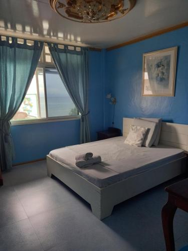 a bedroom with a bed with blue walls and a window at Germaroze in Oslob