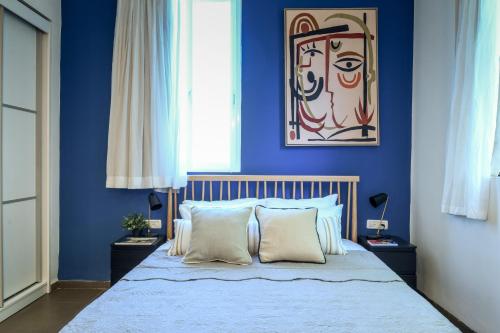 a bedroom with blue walls and a bed with white pillows at The Printhouse - Downtown Boutique Apartments by Sea N' Rent in Haifa