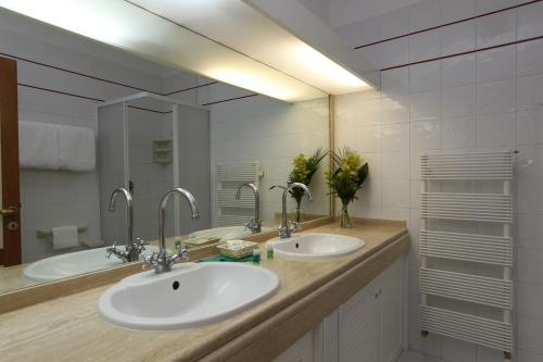 a bathroom with two sinks and a large mirror at Hotel Valle Verde in Procchio