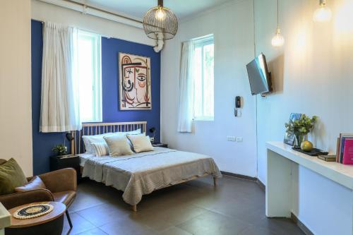 a bedroom with blue walls and a bed and a couch at The Printhouse - Downtown Boutique Apartments by Sea N' Rent in Haifa