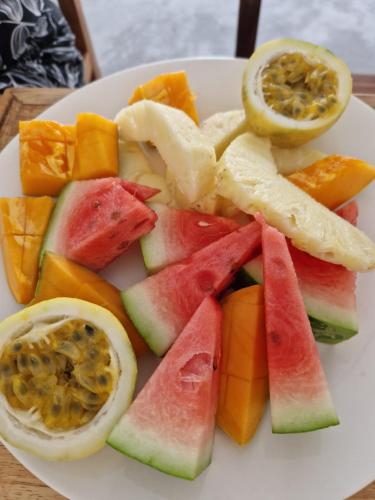 a white plate with fruits and vegetables on a table at Sunny Villa Matemwe in Matemwe