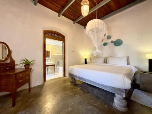 a bedroom with a bed and a desk and a mirror at Foozoo Mantra Weligama in Weligama