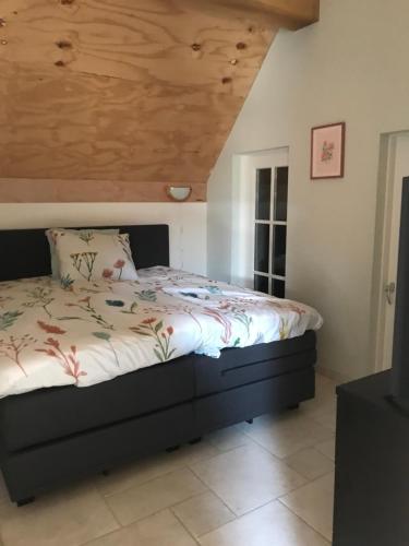 1 dormitorio con 1 cama con techo de madera en De Dagloner, en Nieuwlande