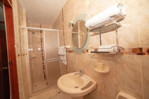 een badkamer met een wastafel en een douche met een spiegel bij Mallmanya Inn in Cuzco