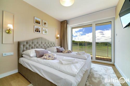 1 dormitorio con 1 cama grande y ventana grande en Apartamenty BalticON Polanki Aqua, en Kołobrzeg