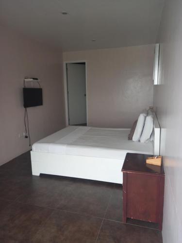 a bedroom with a white bed and a television at Germaroze in Oslob