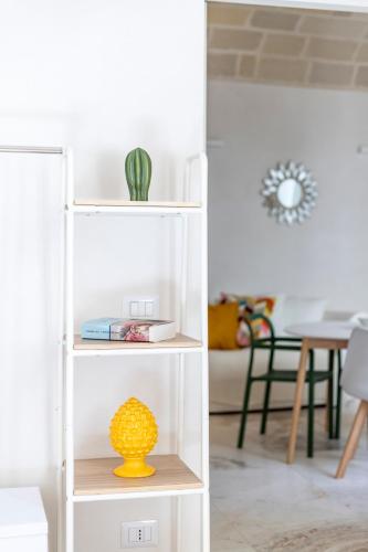 a white book shelf with a yellow vase on it at LE CASE DEL FICO D'INDIA FAVIGNANA in Favignana