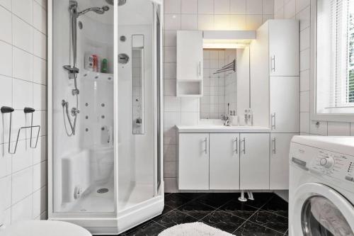 a white bathroom with a shower and a washing machine at Hytte i flott natur in Alta