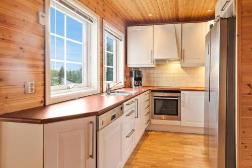 a kitchen with white cabinets and a wooden ceiling at Hytte i flott natur in Alta