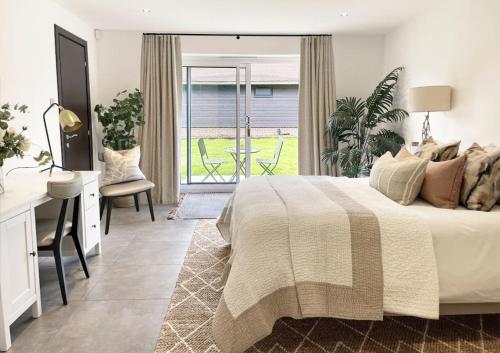 a bedroom with a bed and a desk and a window at The Barn in Chichester