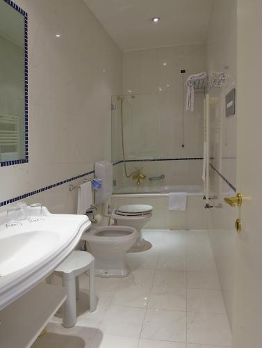 a white bathroom with a toilet and a sink at Hotel Principe in Venice