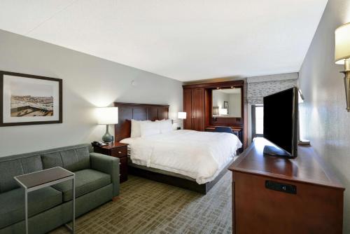 um quarto de hotel com uma cama e uma televisão de ecrã plano em Hampton Inn Detroit Madison Heights South Troy em Madison Heights