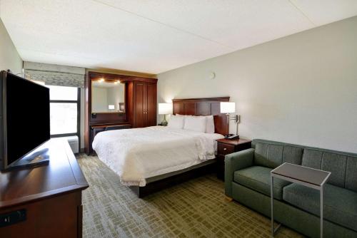 a hotel room with a bed and a couch at Hampton Inn Detroit Madison Heights South Troy in Madison Heights