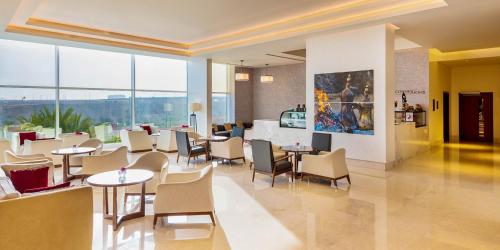 a restaurant with tables and chairs and large windows at Crowne Plaza Muscat OCEC by IHG in Muscat