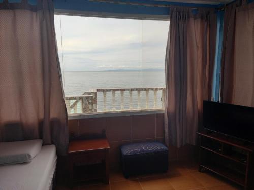 a bedroom with a large window with a view of the ocean at Germaroze in Oslob