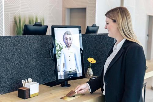 a woman standing at a desk with a computer monitor at GHOTEL hotel & living Bochum in Bochum