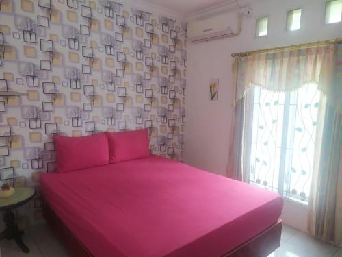 Cama rosa en habitación con ventana en Endah Homestay Syariah, en Purwokerto