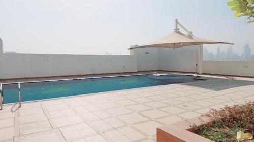 a swimming pool on top of a building with an umbrella at Havana Holiday Homes Oud Metha in Dubai
