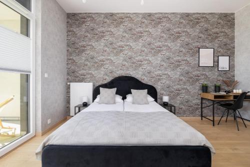 a bedroom with a large bed and a brick wall at Kraków Studio with Parking & Terrace near Zalew Bagry by Renters Prestige in Kraków