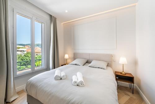 - une chambre avec un grand lit blanc et des chaussons dans l'établissement Centre - 5mn Palais - Plages - Croisette - AX, à Cannes