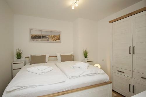a bedroom with a white bed and a cabinet at schöne 2-Raum-Wohnung mit Balkon, gratis Nutzung vom AHOI Erlebnisbad und Sauna in Sellin - Villa Jolie FeWo 09 in Ostseebad Sellin