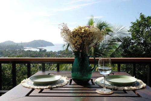 a wooden table with a vase of flowers and a glass at The Love Nest - Stylish One Bed House in Chaloklum